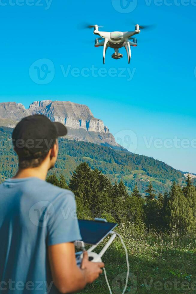 giovane uomo volante fuco su sorprendente montagna paesaggio. uomo operativo un' fuco con a distanza controllo assunzione aereo fotografie e video.