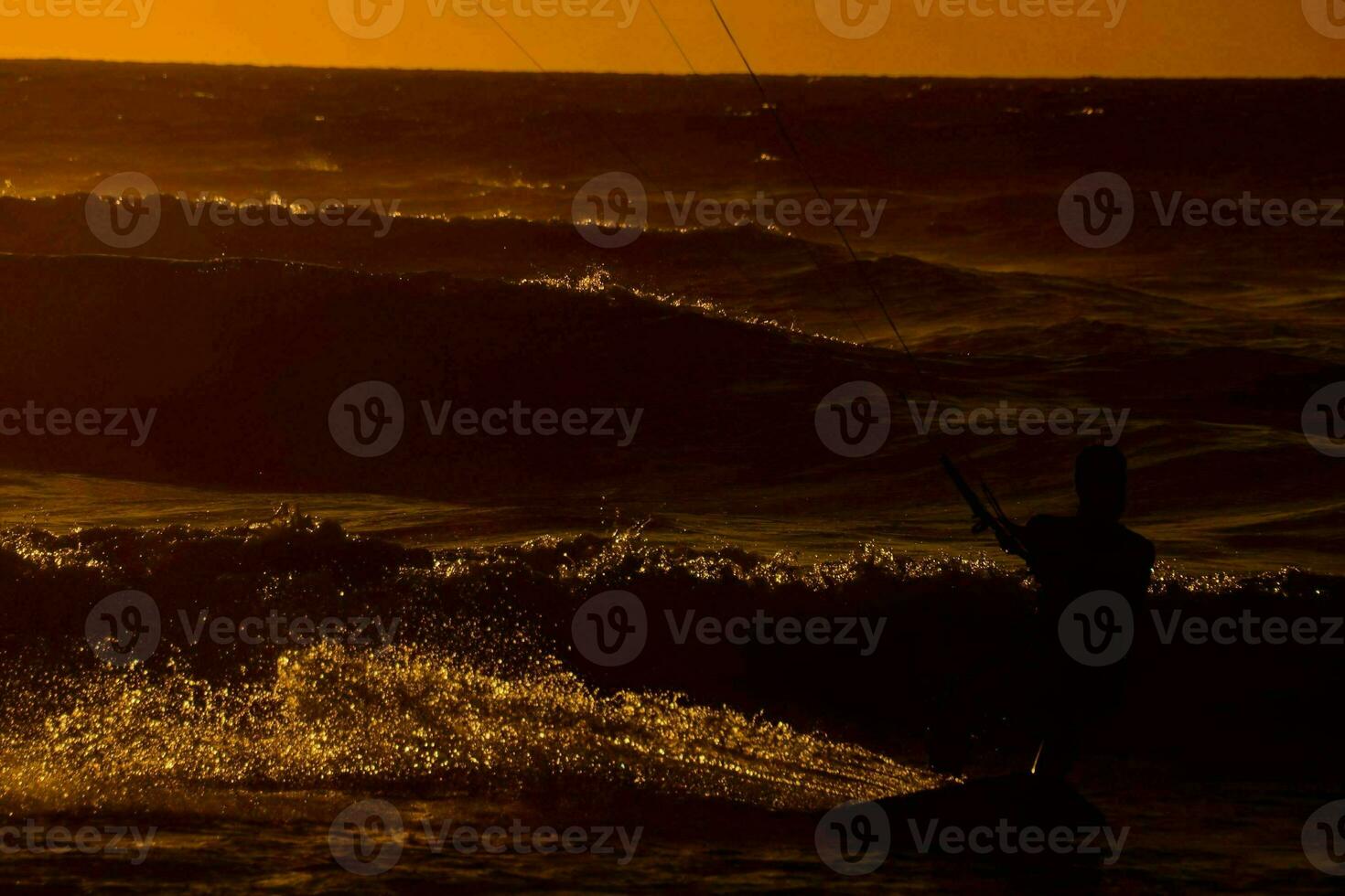 un' uomo aquilone imbarco nel il oceano a tramonto foto