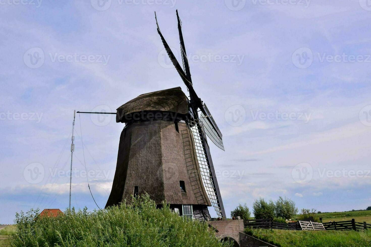 un' mulino a vento è mostrato nel il mezzo di un' campo foto