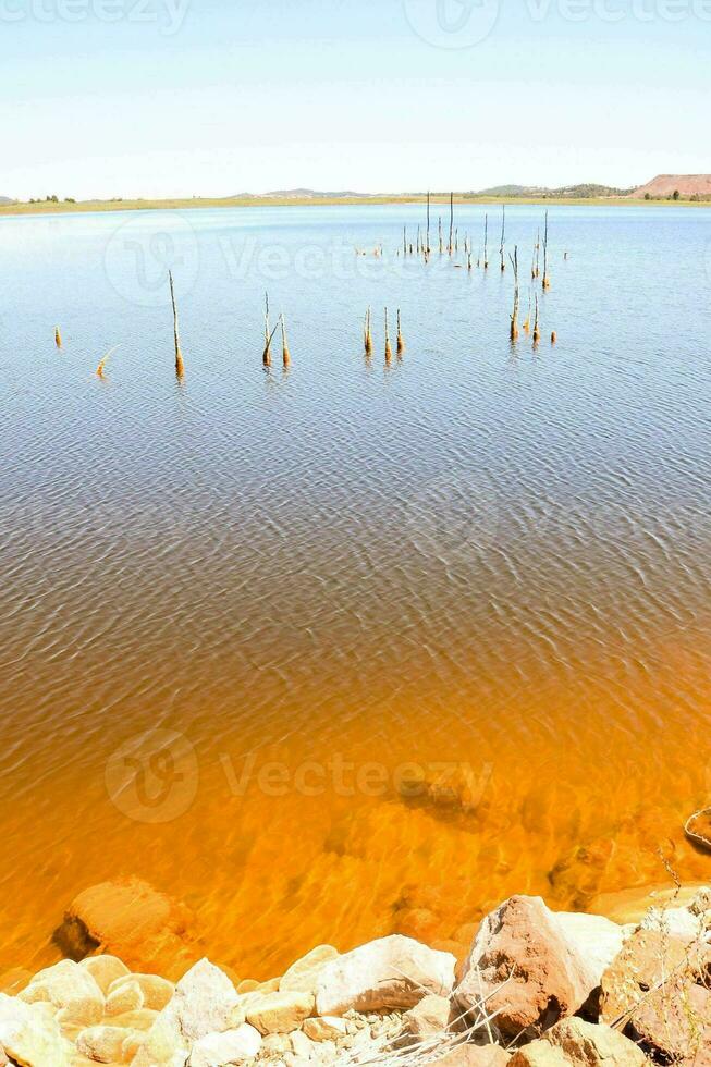 un' lago con arancia acqua e rocce foto