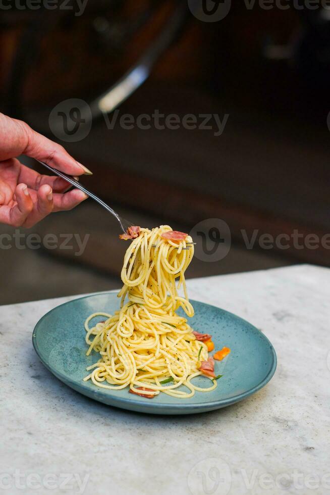 il mano quello è sollevamento il spaghetti su il piatto foto