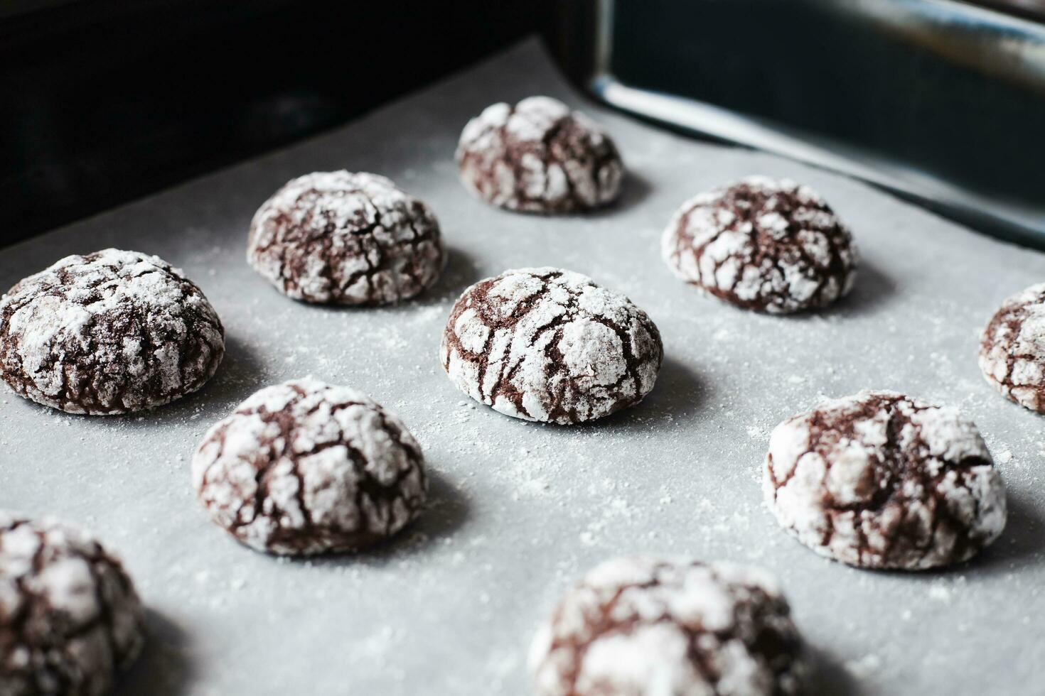 cioccolato biscotti con in polvere zucchero su cottura al forno vassoio. avvicinamento. foto