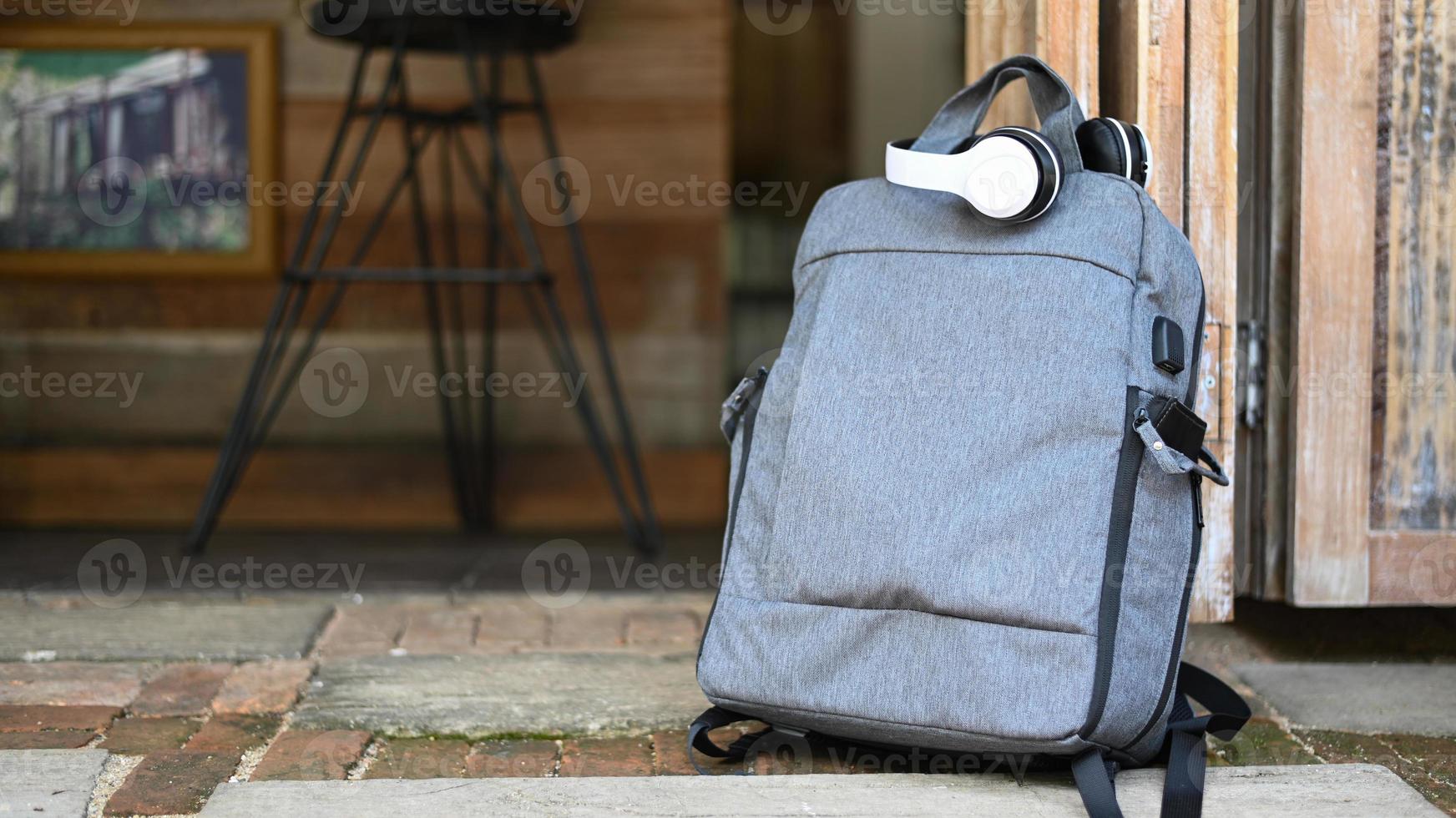 zaino turistico e cuffie poste a terra davanti a una caffetteria, concetto di viaggio. foto