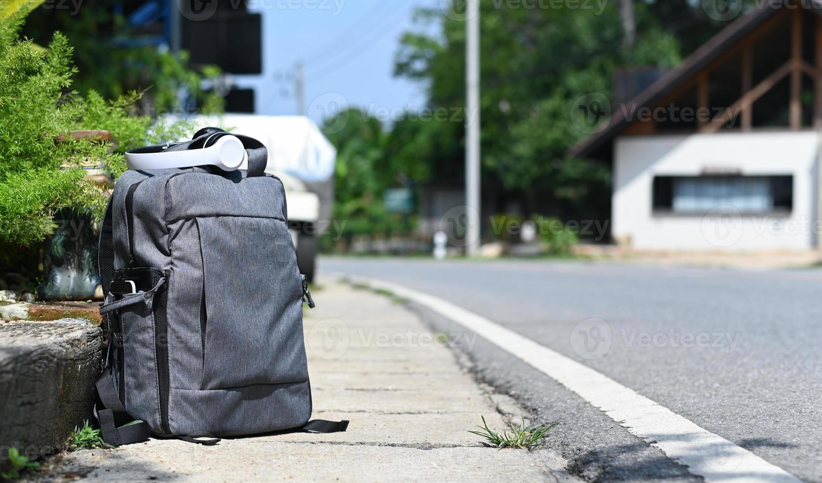 zaino con cuffie poste sul ciglio della strada in attesa di un viaggio, concetto di viaggio. foto