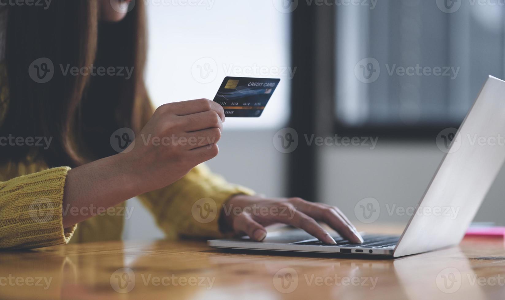 giovane donna che utilizza computer portatile e tiene in mano una carta di credito, concetto di shopping online, pagamento online con carta di credito. foto