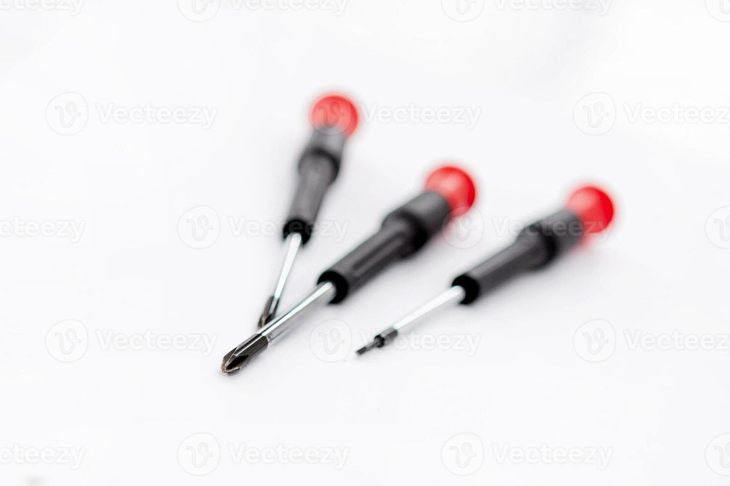 avvicinamento servizio fotografico di tre rosso e nero maneggiato cacciaviti su un' bianca sfondo foto
