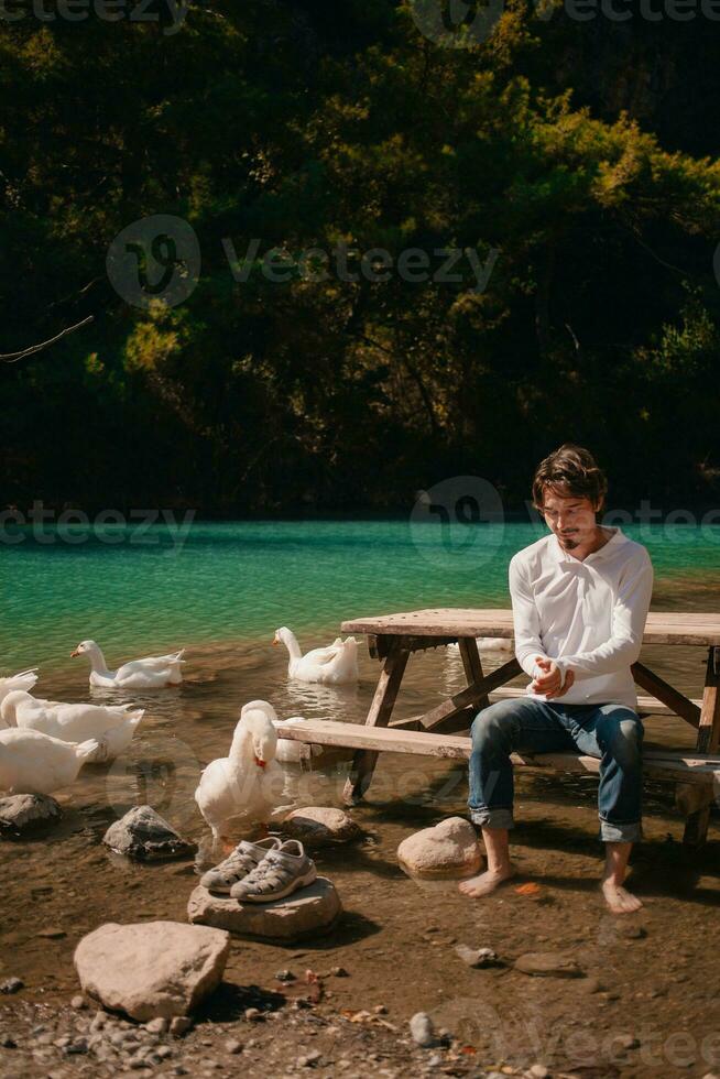 un' uomo gode un' vacanza nel il montagne su un' lago nel tacchino Il prossimo per bianca oche. ritratto foto