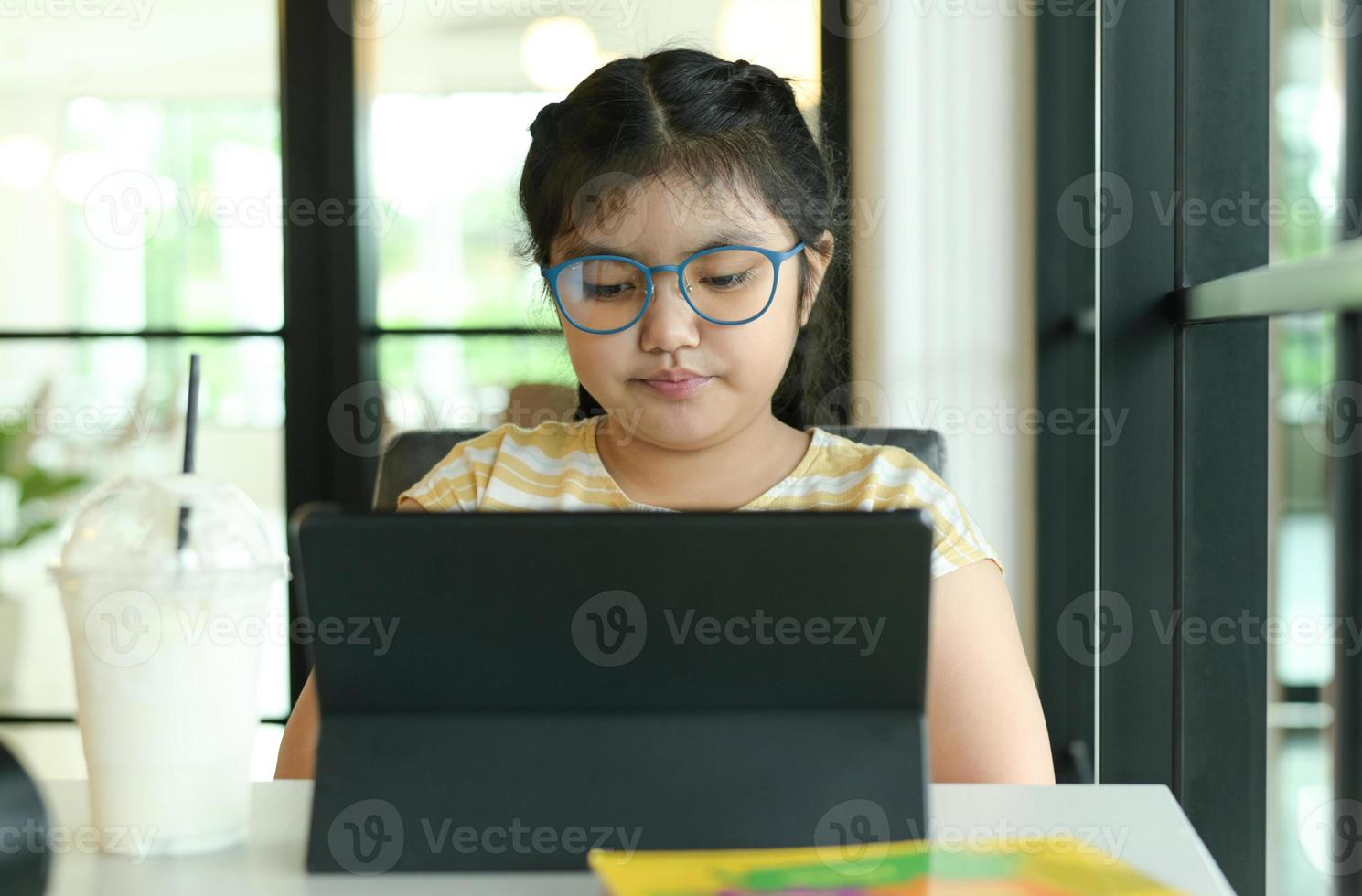 una ragazza con gli occhiali studia online con un tablet. foto