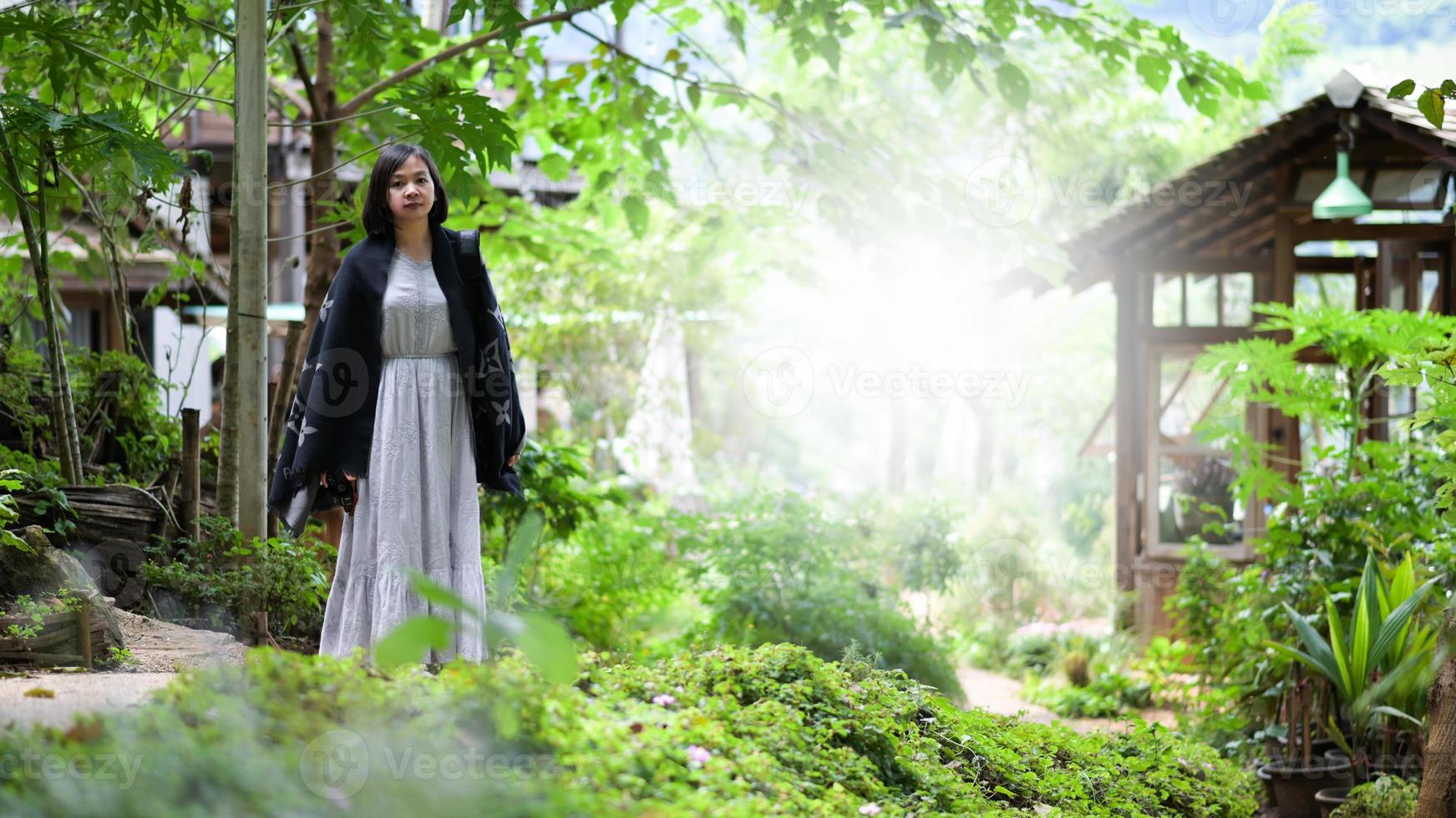 donna asiatica che cammina felicemente e scatta foto nel parco naturale.