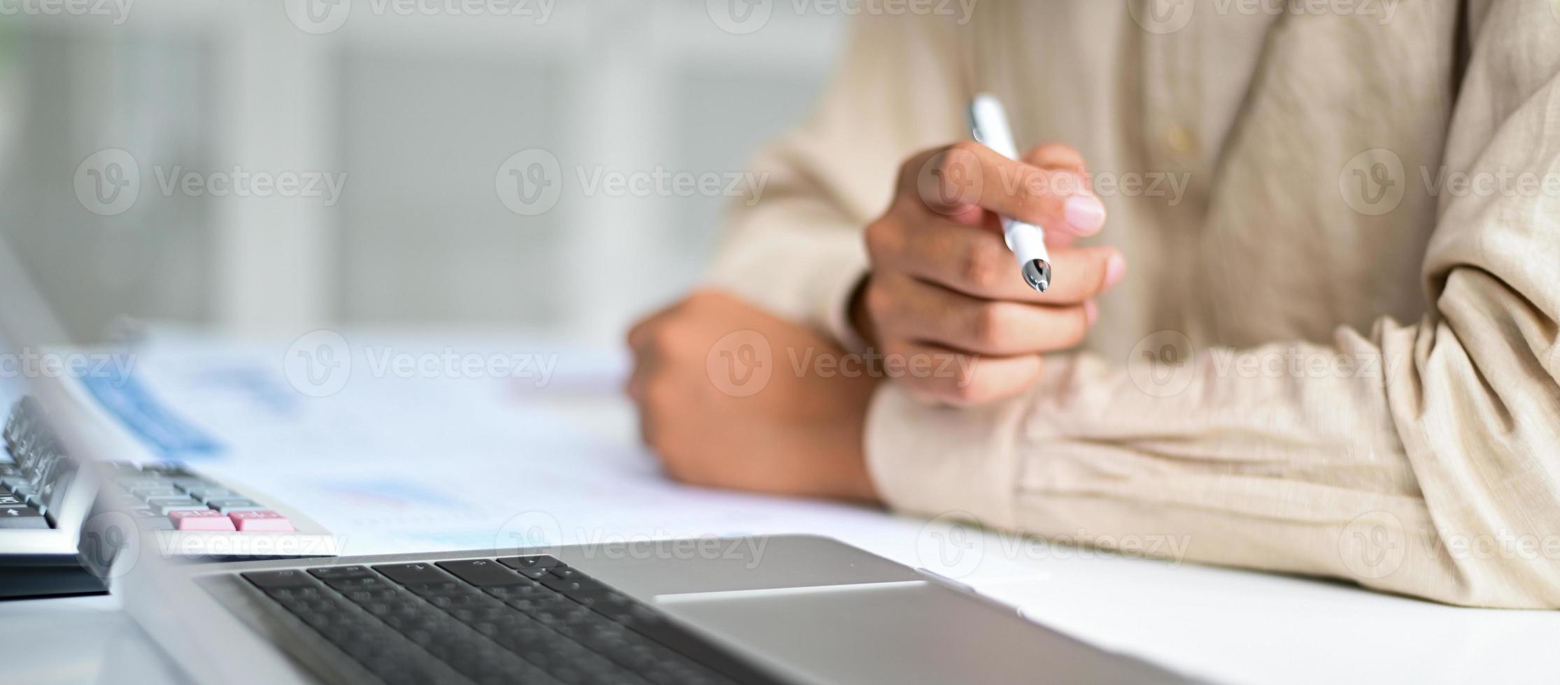 colpo ritagliato di uomo d'affari che tiene la penna in mano sulla scrivania, concetti di business. foto