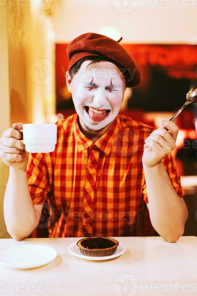 il clown è mangiare un' torta nel un' bar e il suo viso è gracchiare. foto