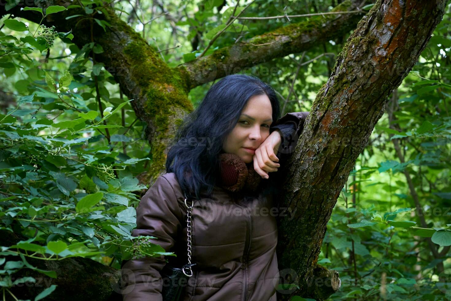 grave giovane misterioso brunetta donna.diffusione albero nel un coperto di vegetazione foresta foto