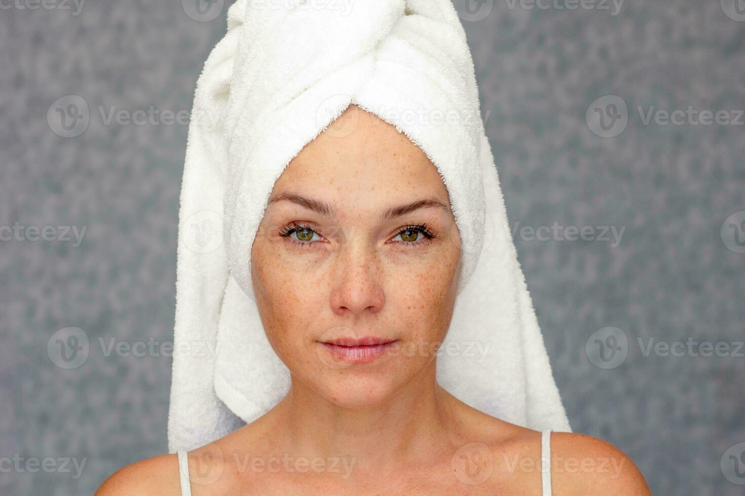ritratto di caucasico mezzo anziano donna di anni 40 con asciugamano su testa guardare a telecamera foto
