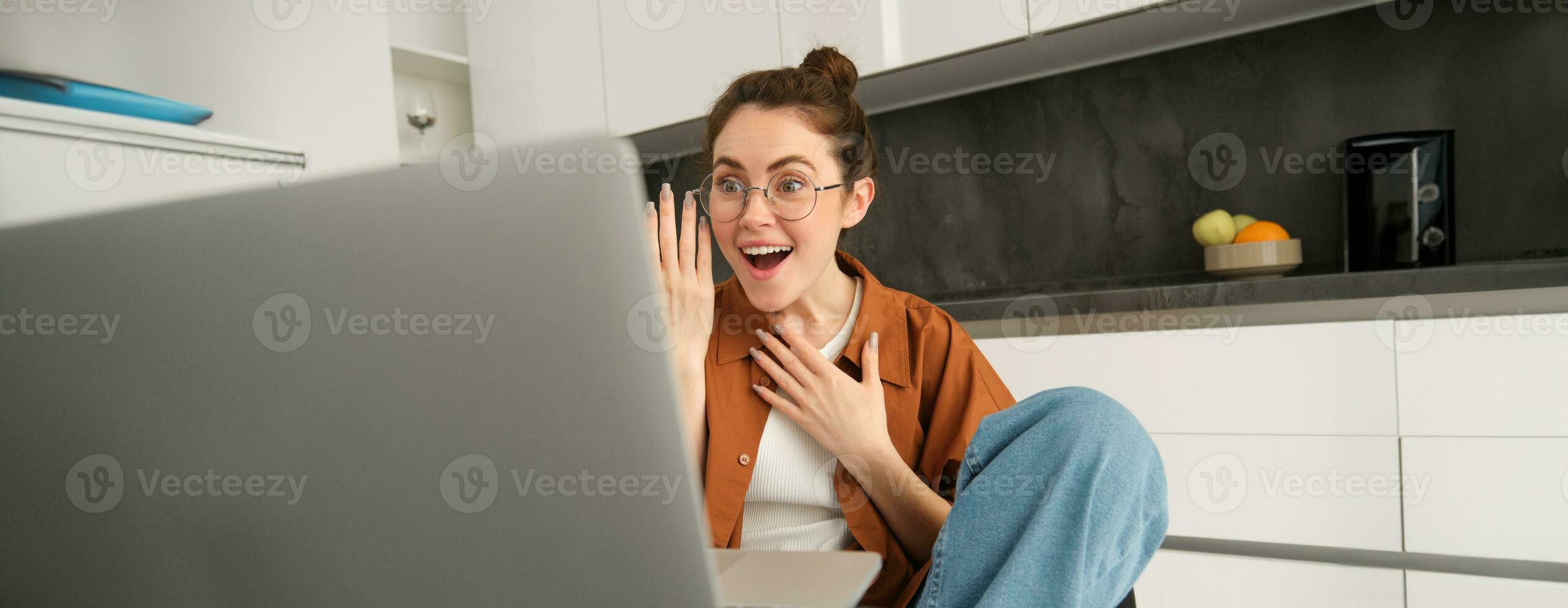 ritratto di bellissimo giovane donna in linea chat con amico su computer portatile, si connette per video conversazione, parlando attraverso computer, guardare sorpreso e contento foto