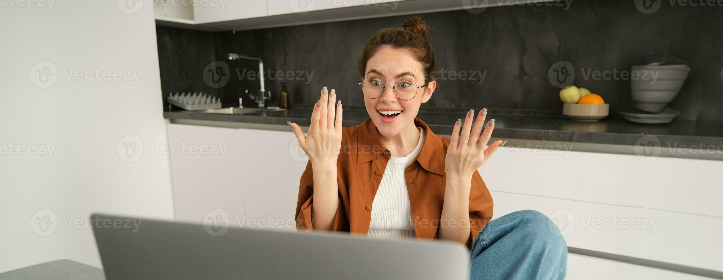 ritratto di sorpreso, contento donna nel occhiali, guardare a il computer portatile con stupito, eccitato viso espressione, positivo reazione per grande notizia foto