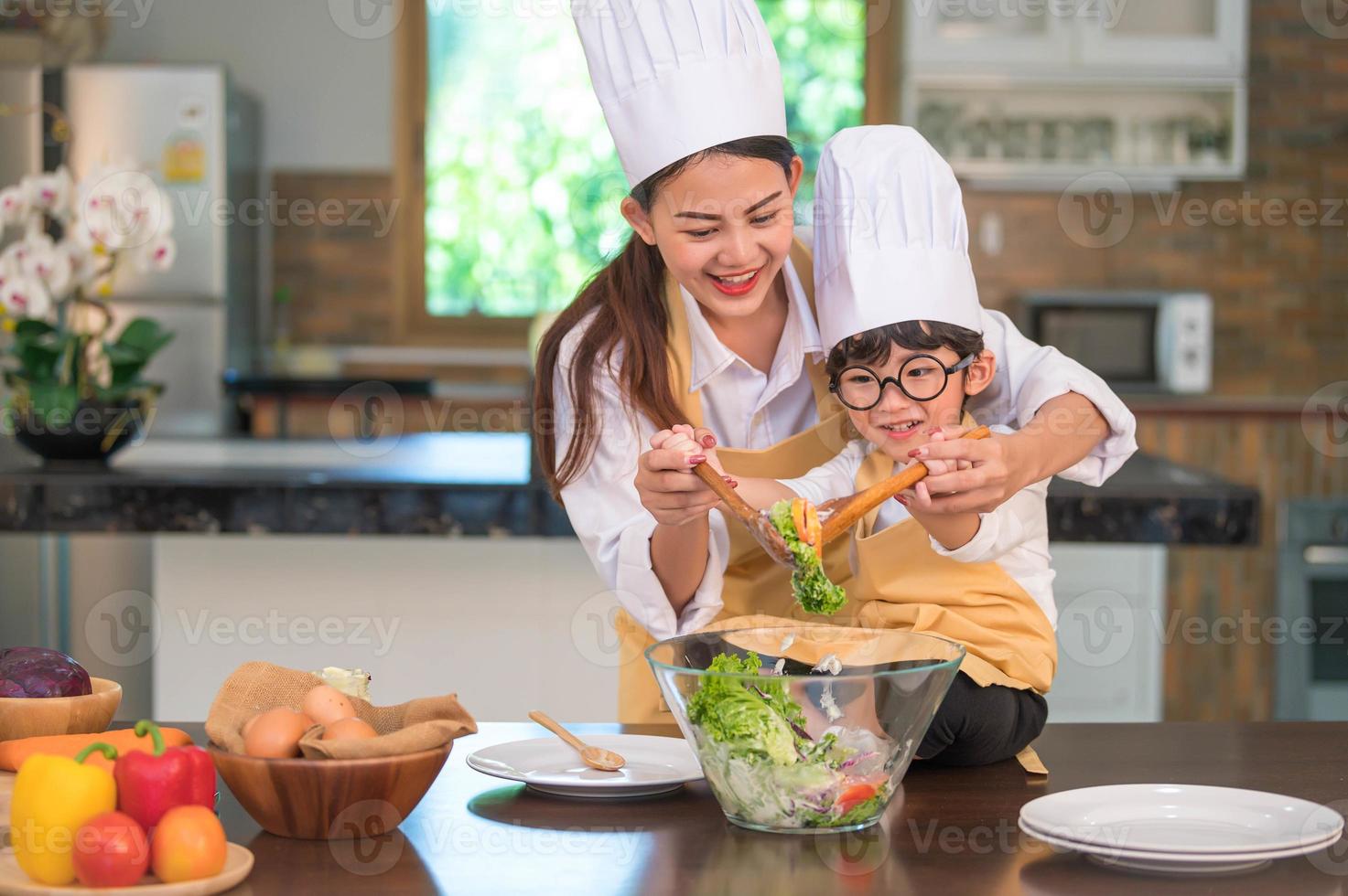 felice bella donna asiatica e simpatico ragazzino con gli occhiali si preparano a cucinare in cucina a casa. stili di vita delle persone e della famiglia. concetto di cibo e ingredienti fatti in casa. due persone tailandesi vita foto