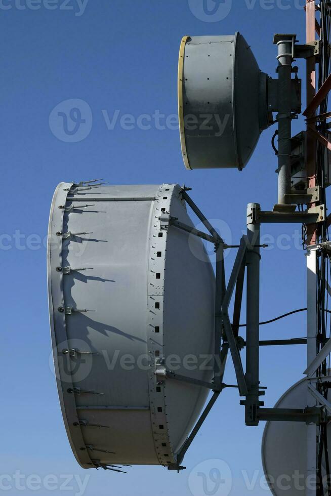 telecomunicazione antenna con multiplo satellitare contro il blu cielo foto