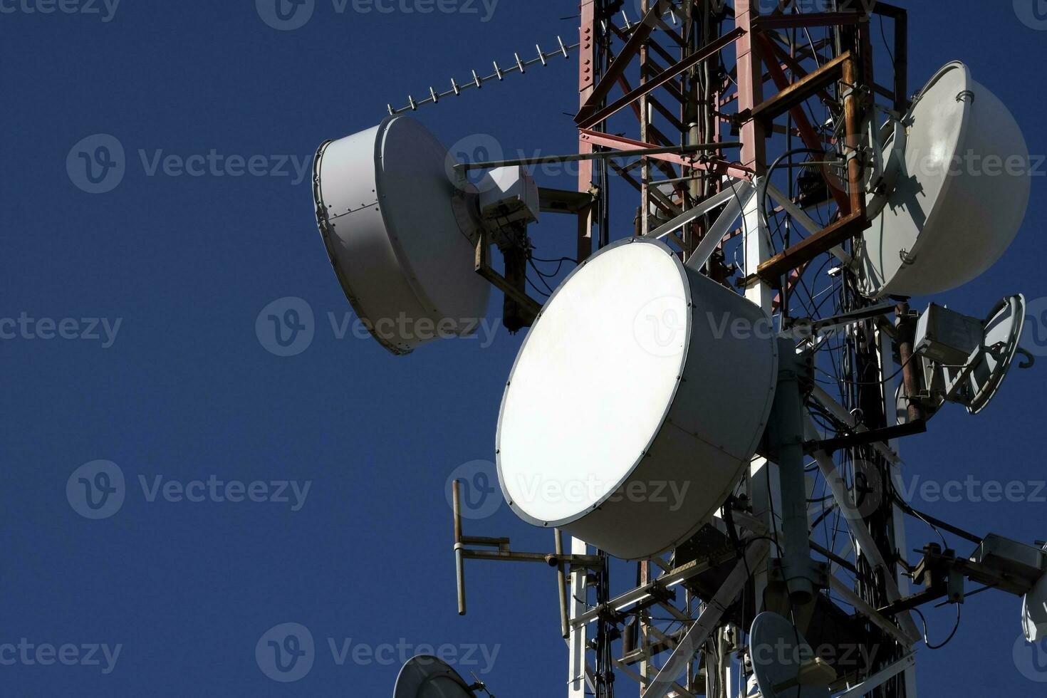 telecomunicazione antenna con multiplo satellitare contro il blu cielo foto