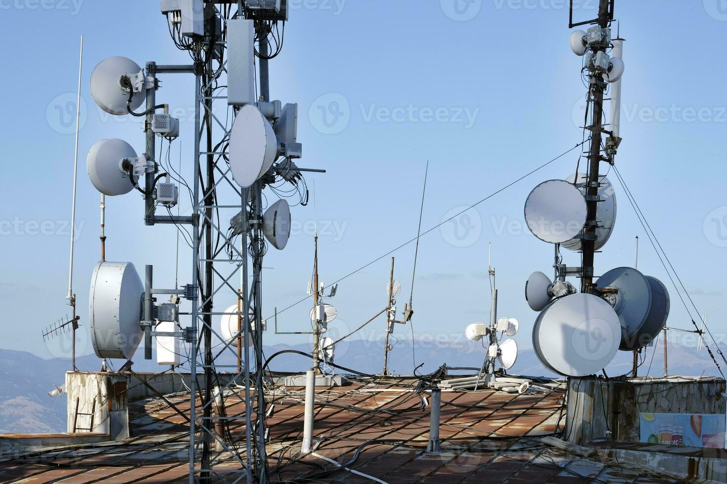 telecomunicazione antenna con multiplo satellitare contro il blu cielo foto