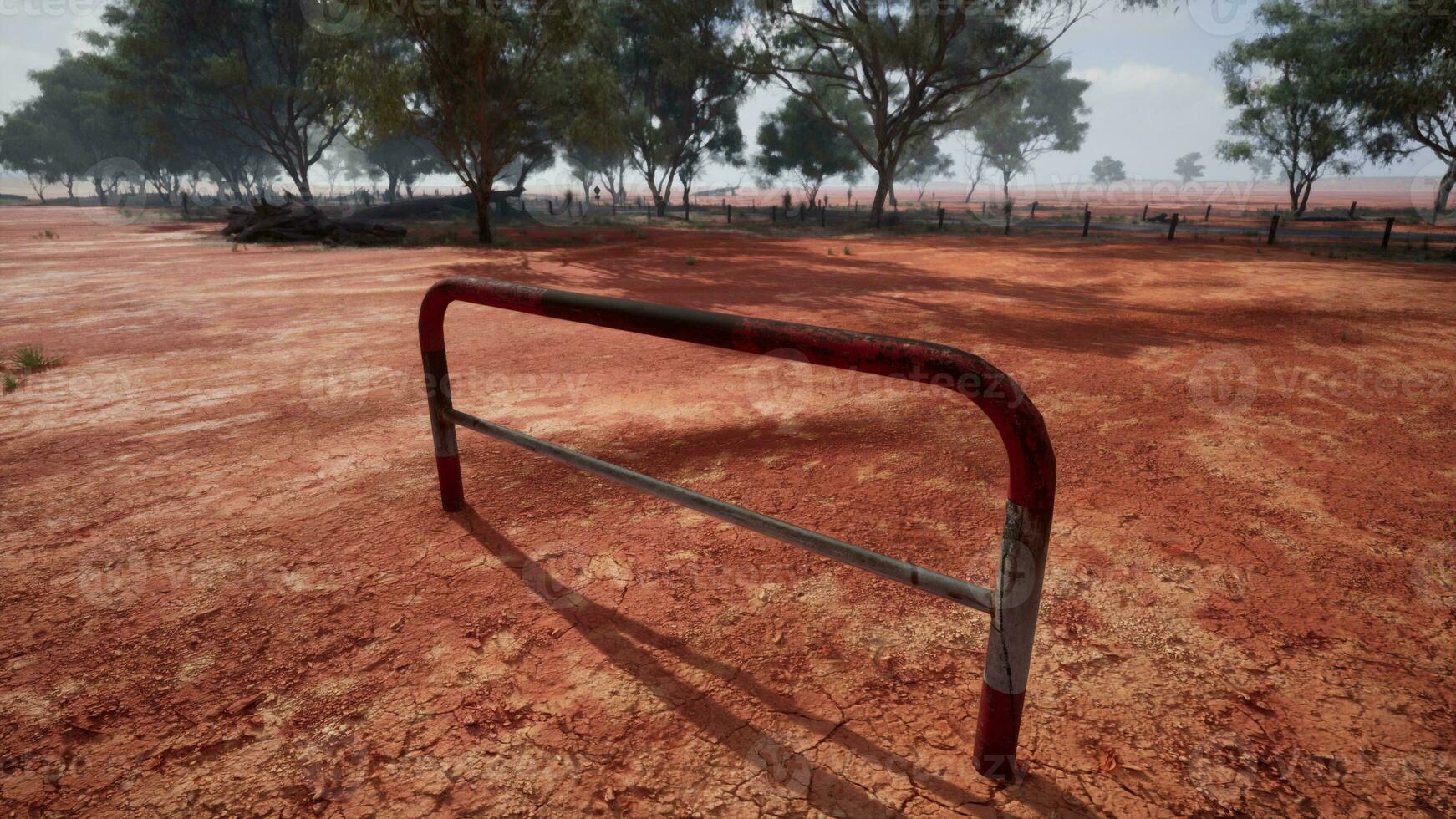 un' rustico rosso sporco campo con un' affascinante recinto e alberi nel il sfondo foto