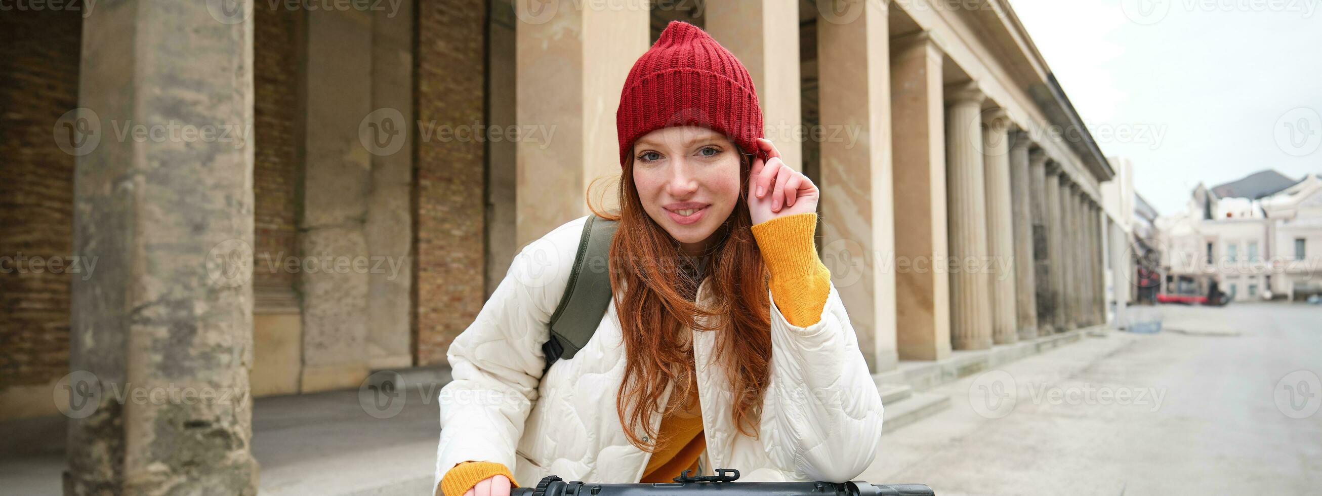 sorridente testa Rossa europeo ragazza unità pubblico scooter, turista esplora città, cavalcate nel città centro foto