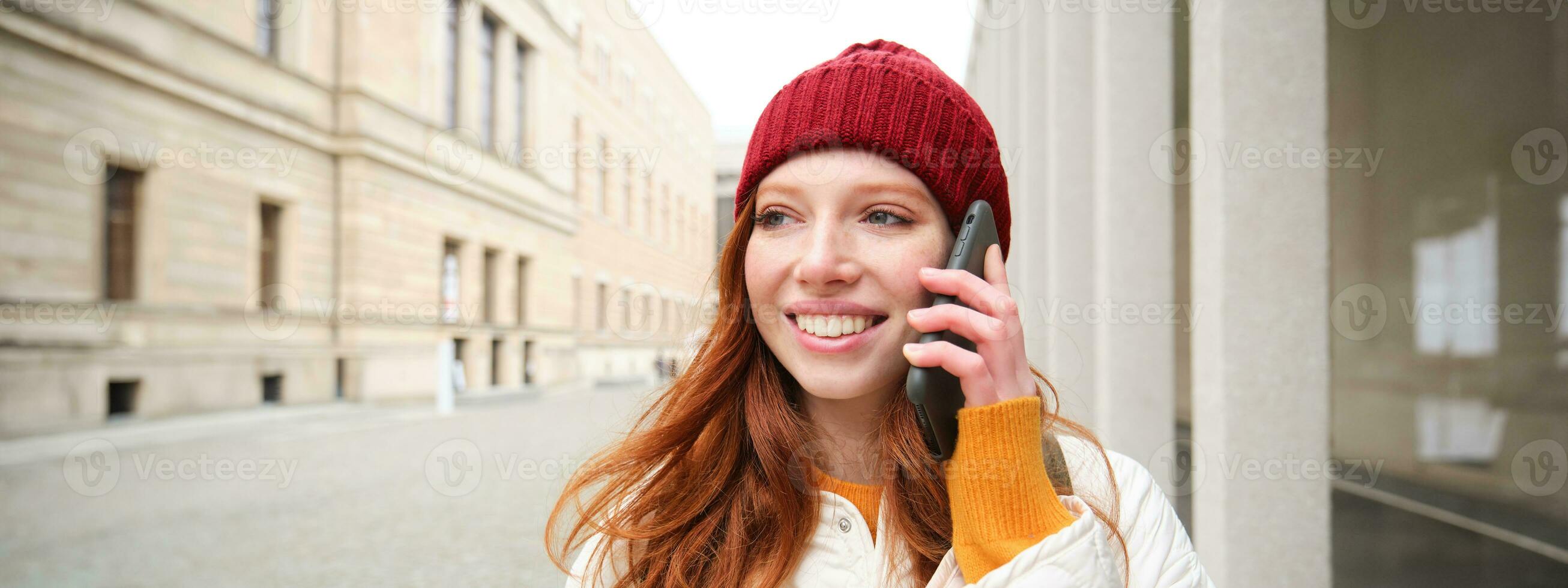 contento testa Rossa donna, ragazza con Telefono colloqui, ha conversazione su mobile app, usi Internet per chiamata all'estero con smartphone app, ridendo e sorridente foto