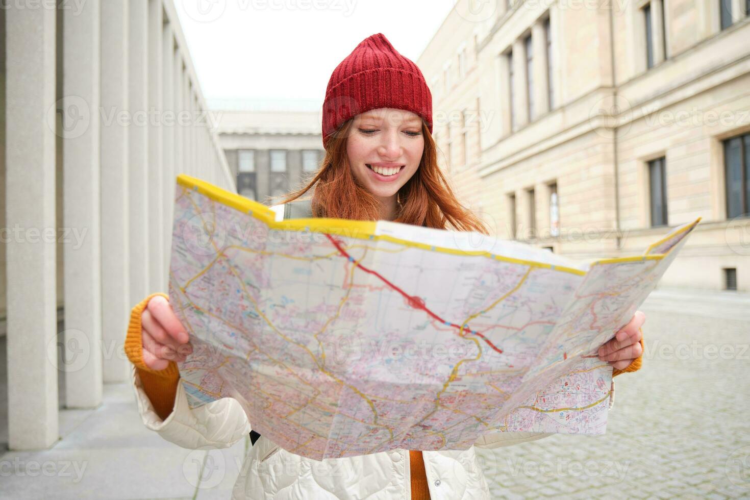 testa Rossa ragazza, turista esplora città, sembra a carta carta geografica per trova modo per storico punti di riferimento, donna su sua viaggio in giro Europa ricerche per giro turistico foto
