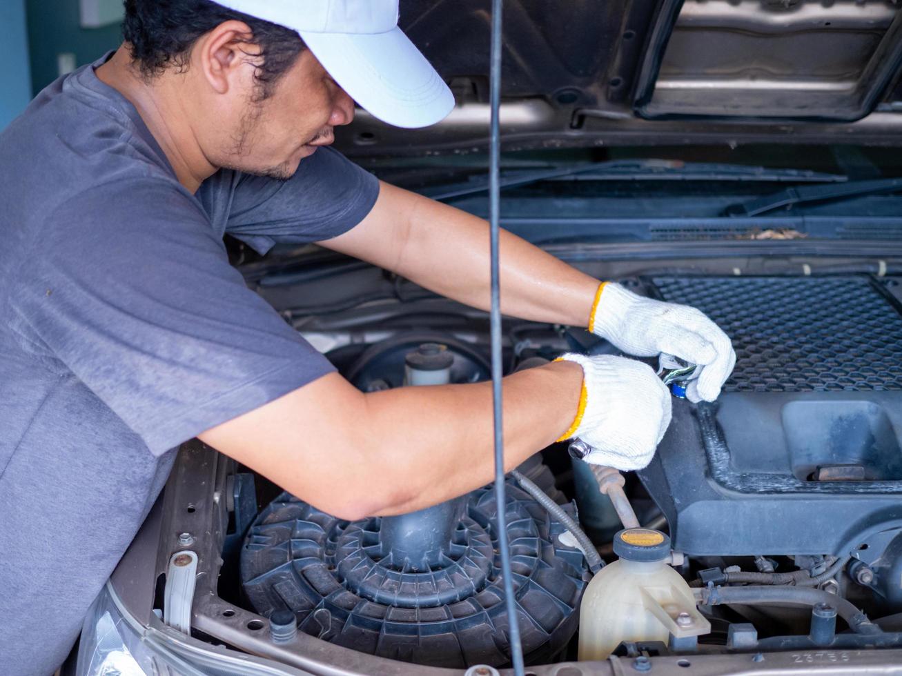 meccanico che tiene in mano una chiave inglese durante la riparazione di un'auto. foto