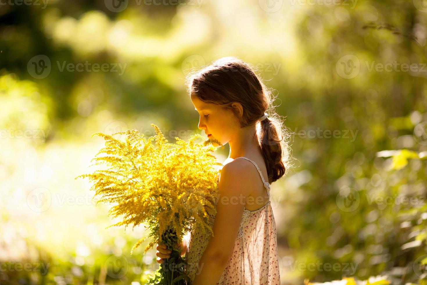 bambina in piedi con un mazzo di fiori di campo foto