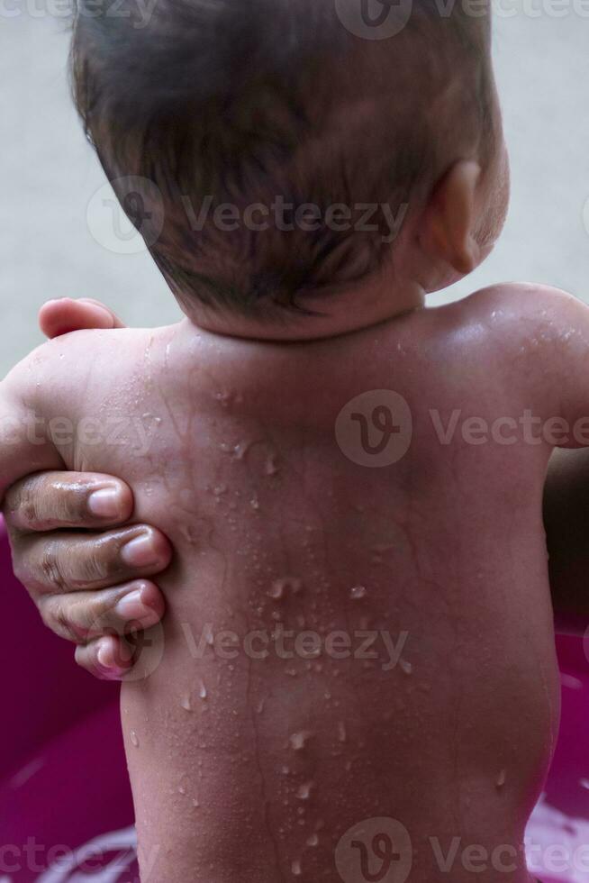 carino asiatico neonato bambino bagnarsi nel vasca da bagno madre bagna figlia con caldo acqua contento sorridente carino neonato bambino nel un' rilassante e confortevole vasca da bagno. concetti per cura per neonati. foto