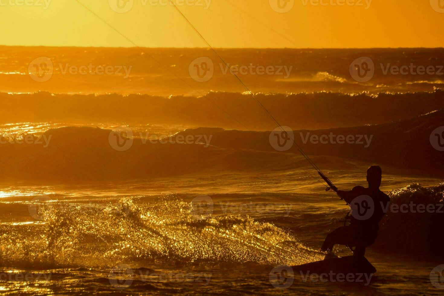 un' uomo kiteboarding nel il oceano a tramonto foto