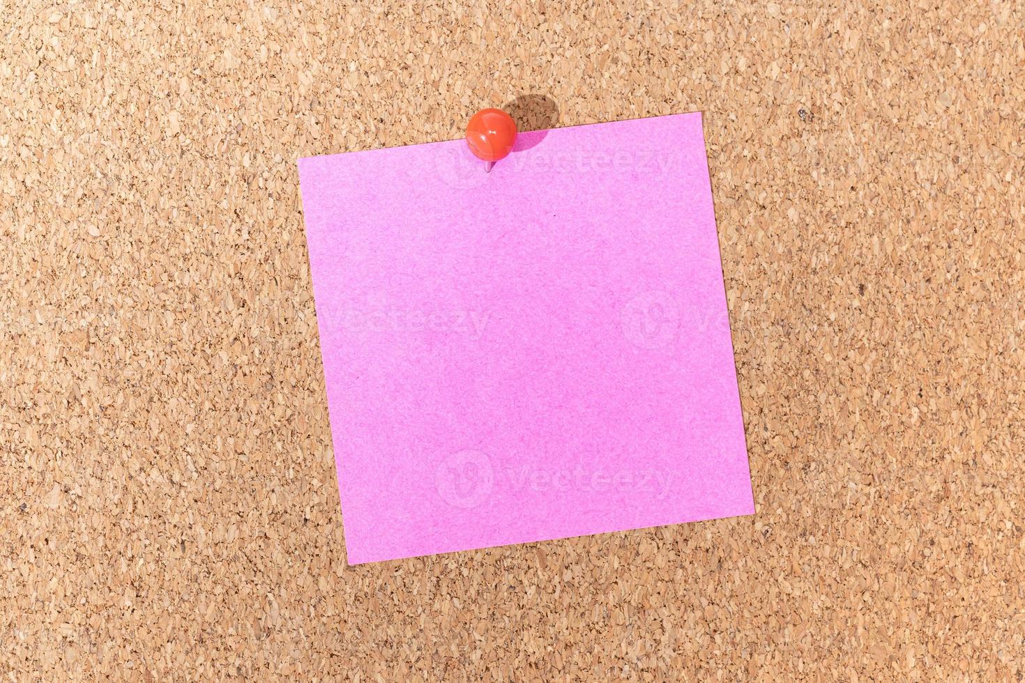 nota rosa vuota e puntina a pressione sulla bacheca di sughero. modello per testo o disegni dell'annuncio foto
