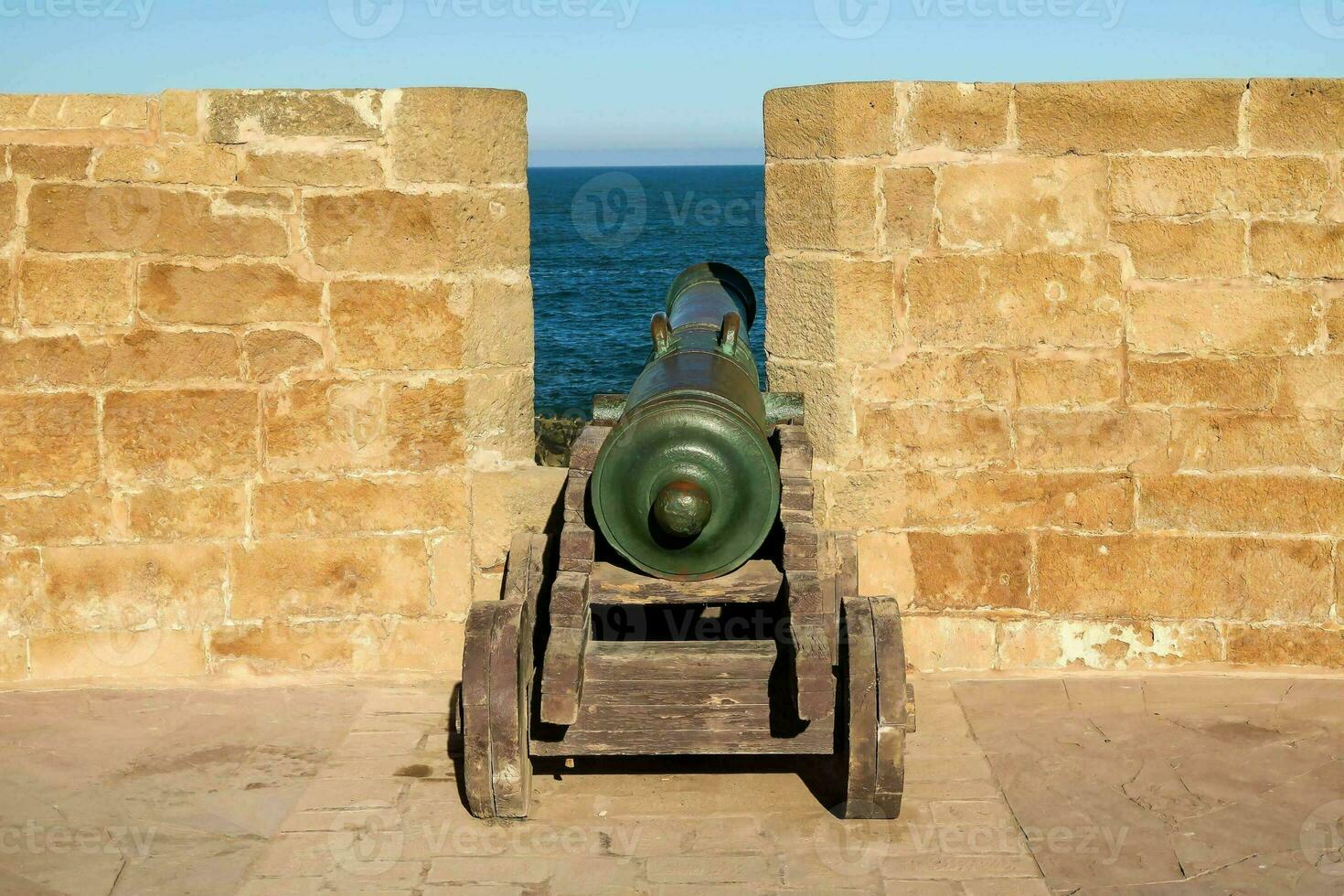 un' cannone è seduta nel un' pietra parete vicino il oceano foto