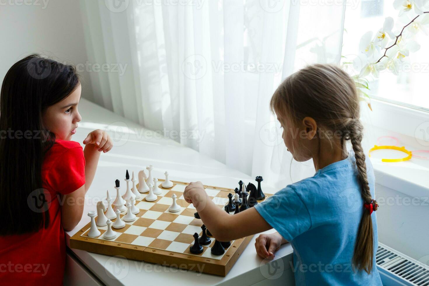 due bambini carini che giocano a scacchi a casa foto
