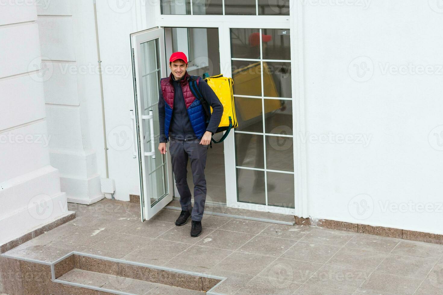 ritratto di un' allegro consegna uomo in piedi con giallo termo zaino per cibo consegna su il strada all'aperto foto