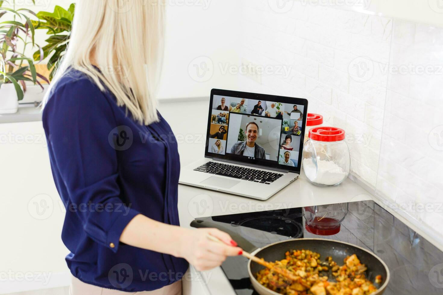 bellissimo ragazza è apprendimento per cucinare salutare cibo in linea di il Internet a partire dal un' il computer portatile nel grigio cucina su tavolo. foto