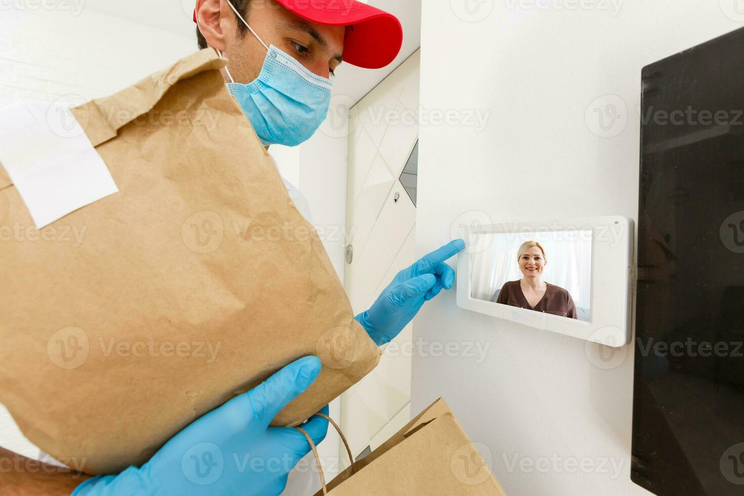 casa consegna, in linea ordine. un' uomo nel uniforme, un' medico maschera e gomma da cancellare guanti con un' scatola, un' pacco nel il suo mani. cibo e cibo consegna durante il quarantena di il coronavirus pandemia foto