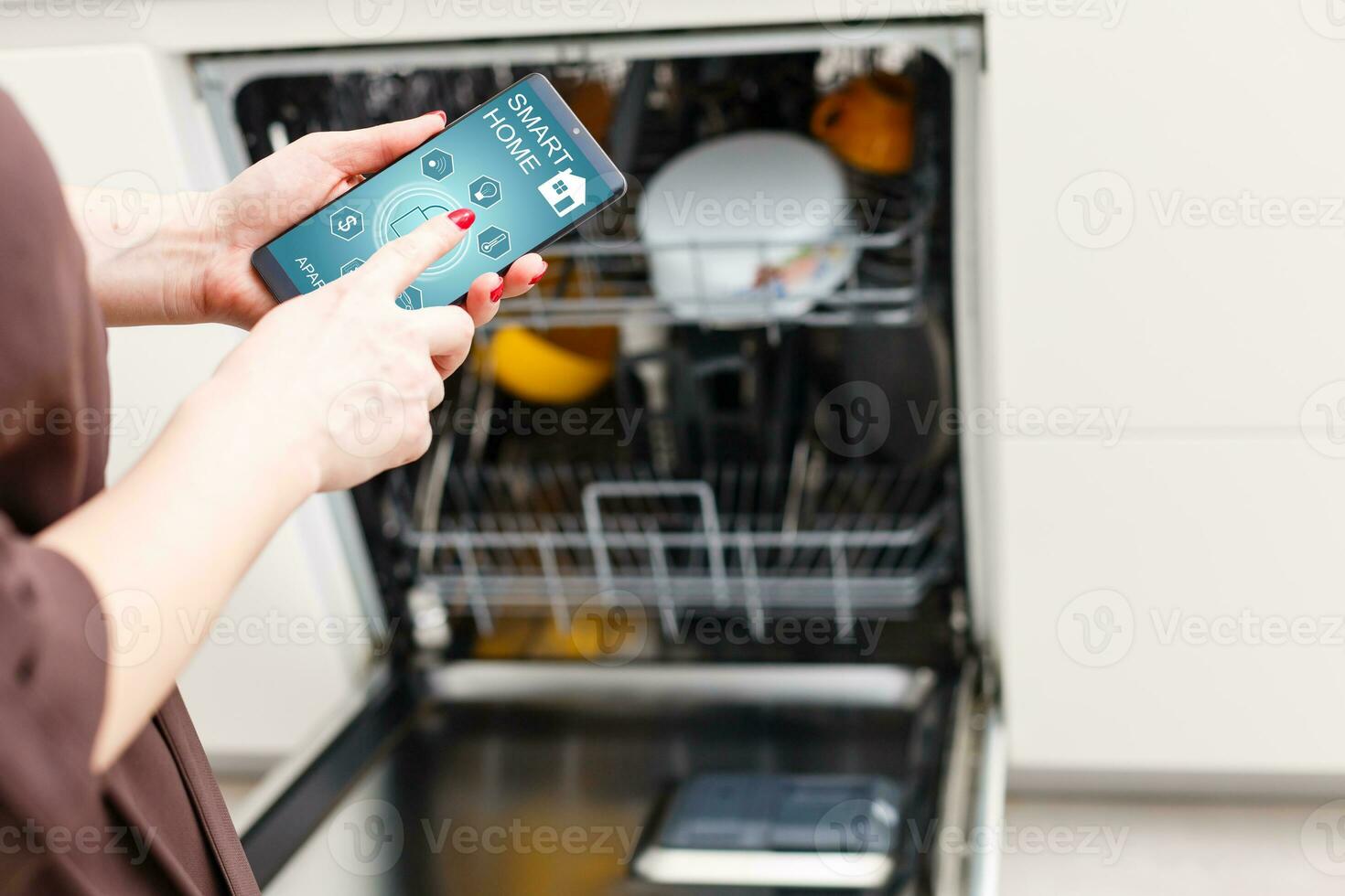 avvicinamento di donna di mano mostrando lavastoviglie App su mobile Telefono nel cucina foto
