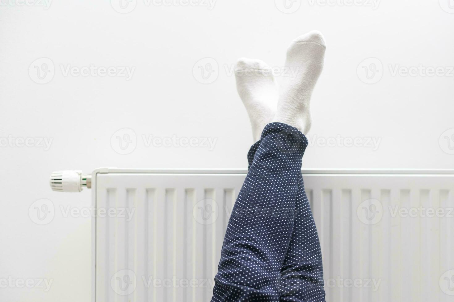 donna riscaldamento su con piedi su riscaldatore inverno calzini essiccazione su un' riscaldatore foto