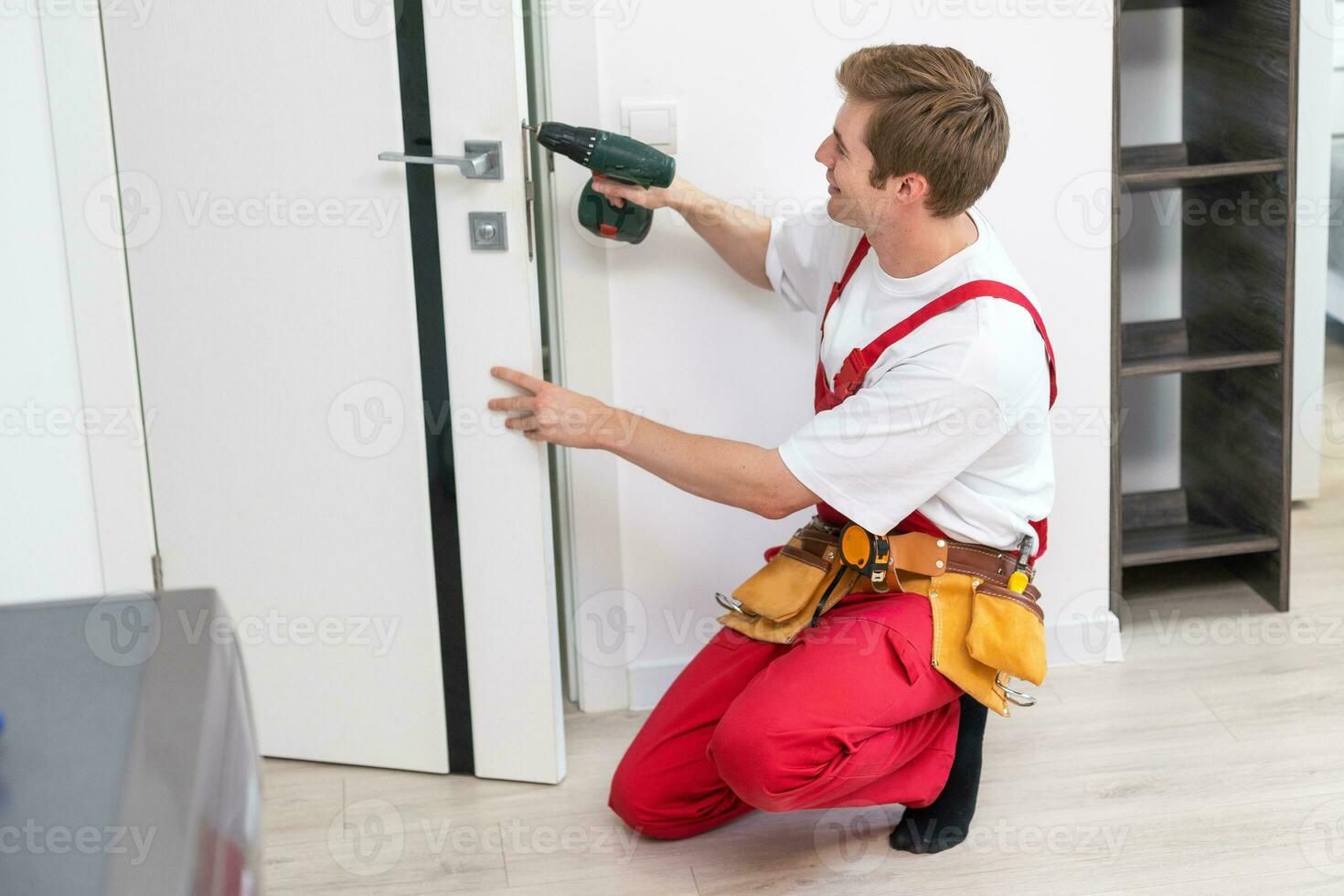 perforazione e installazione di interno porte, il artigiano fa un' buco nel il porta telaio con un' mano trapano, porte e installazione. foto