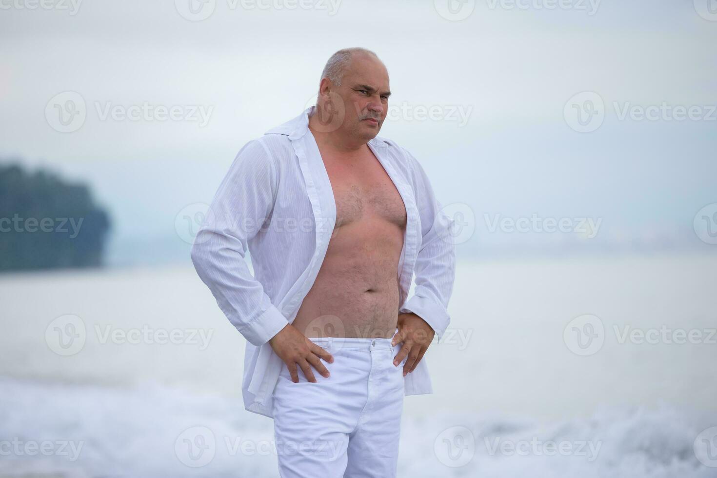 bello anziano uomo di atletico costruire nel leggero Abiti su il spiaggia. foto