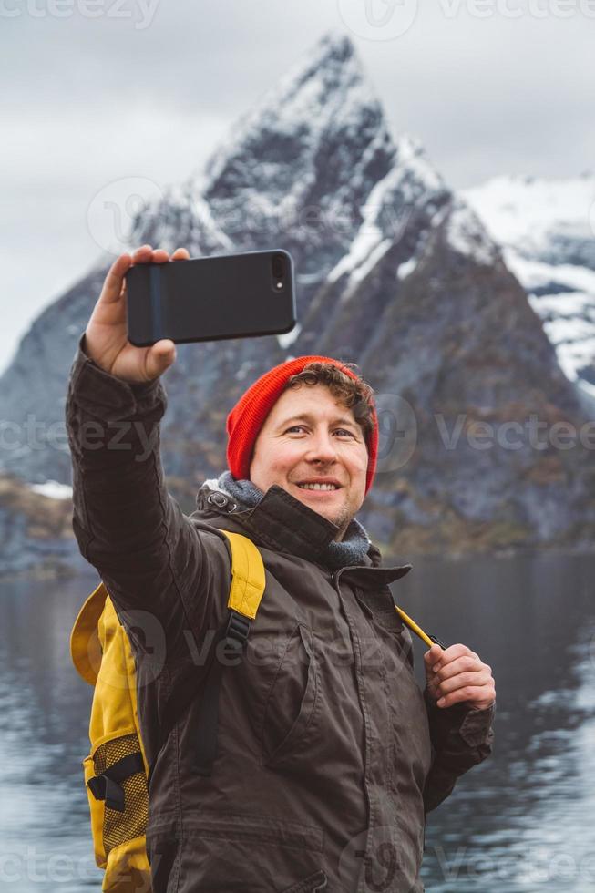 uomo viaggiatore ritratto che scatta autoritratto una foto con uno smartphone sullo sfondo di una montagna