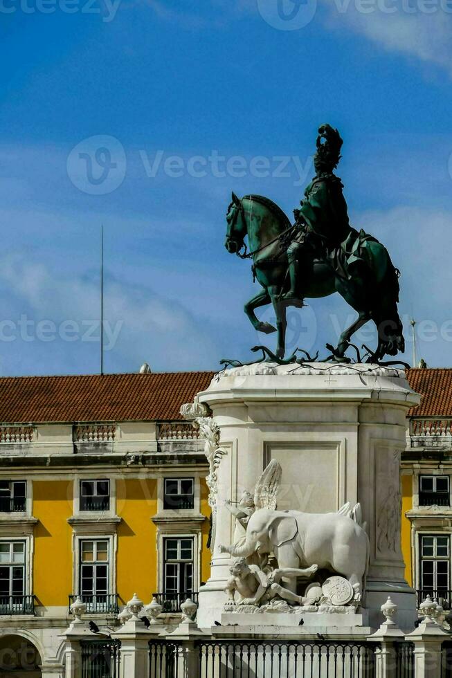 un' statua di un' uomo su un' cavallo nel davanti di un' giallo edificio foto
