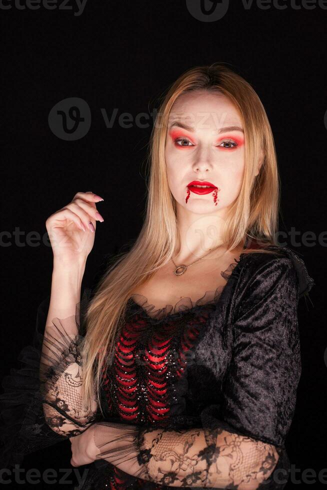 caucasico ragazza vestito su piace un' vampiro per Halloween al di sopra di nero sfondo. foto