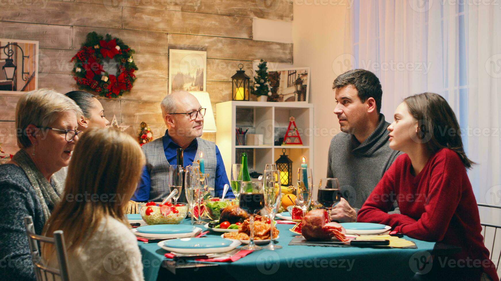 nonna parlando con poco nipotina a Natale riunione. tradizionale festivo Natale cena nel multigenerazionale famiglia. godendo natale pasto festa nel decorato camera. grande famiglia riunione foto