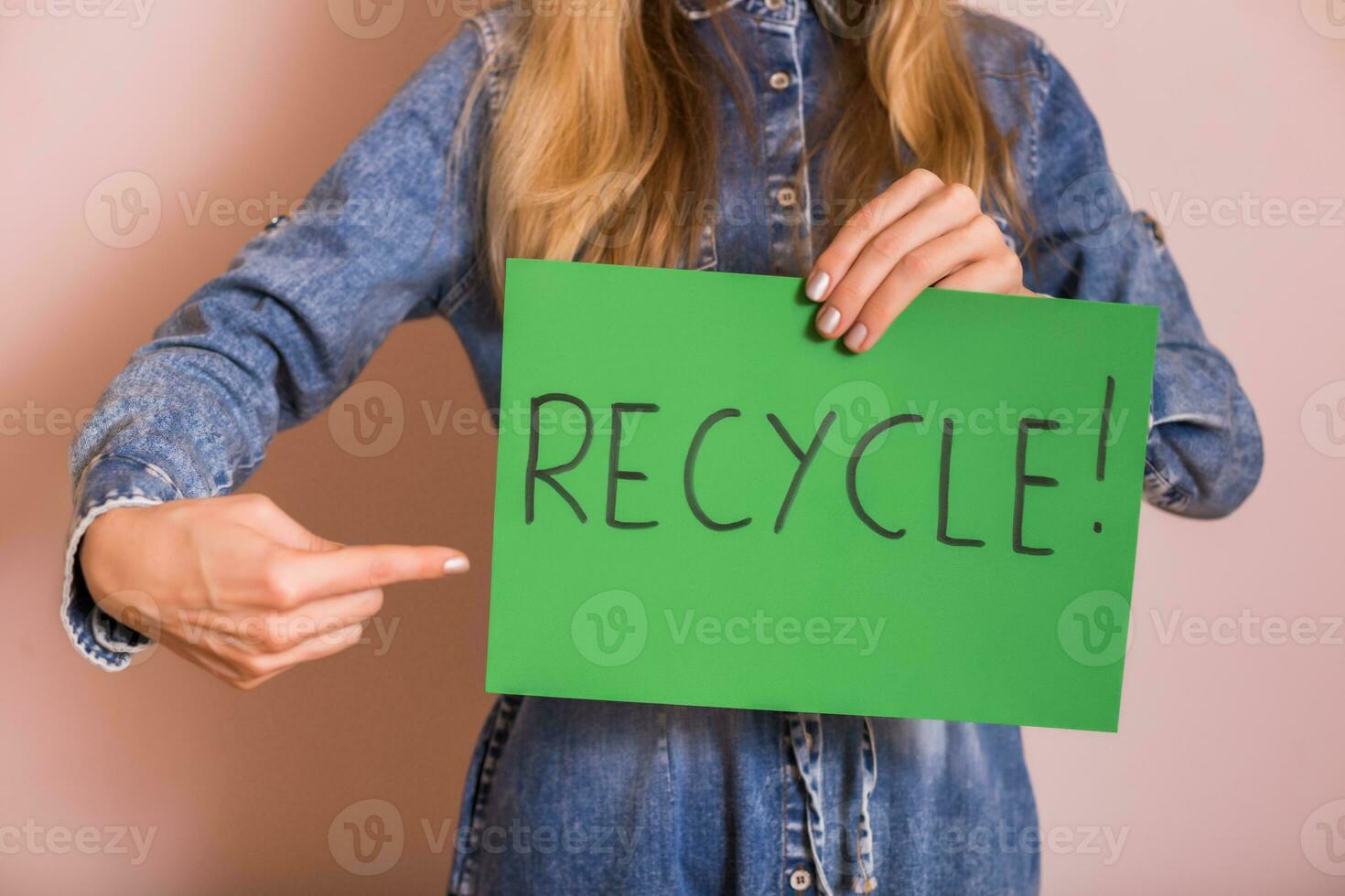 donna in piedi nel davanti di parete e Tenere verde carta con parola riciclare. foto
