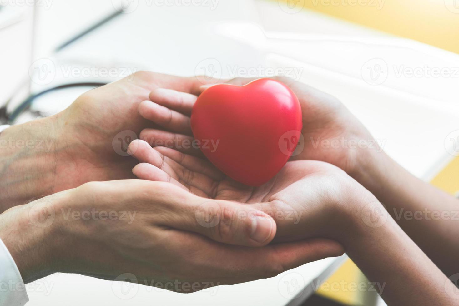 mani del medico che tengono e danno il cuore rosso del massaggio al paziente foto