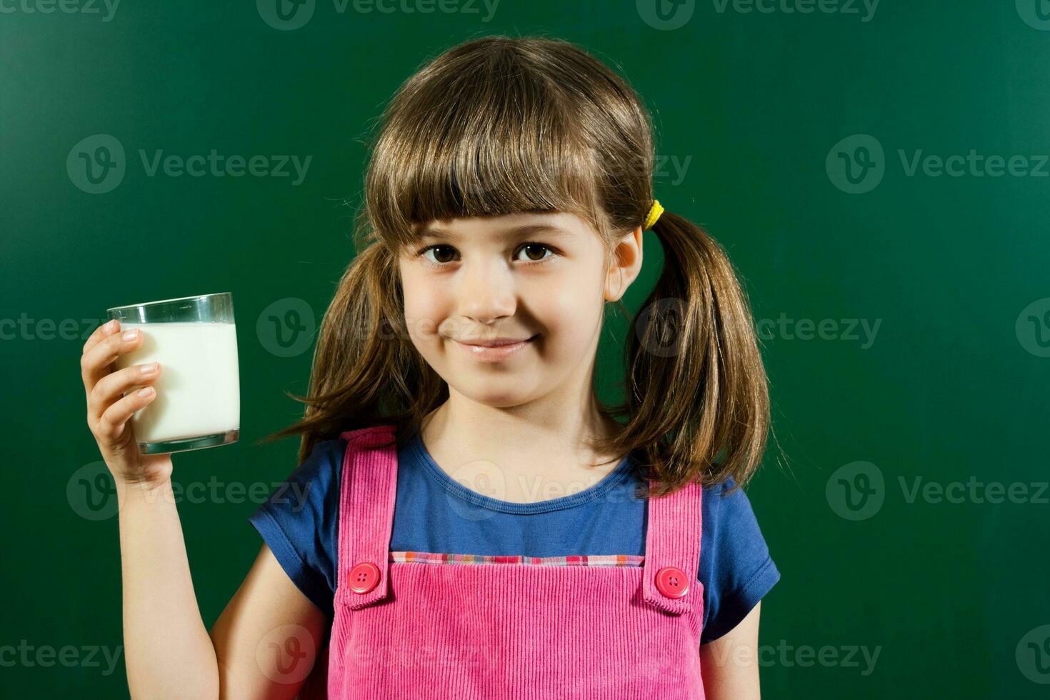 poco ragazza con bicchiere di latte foto