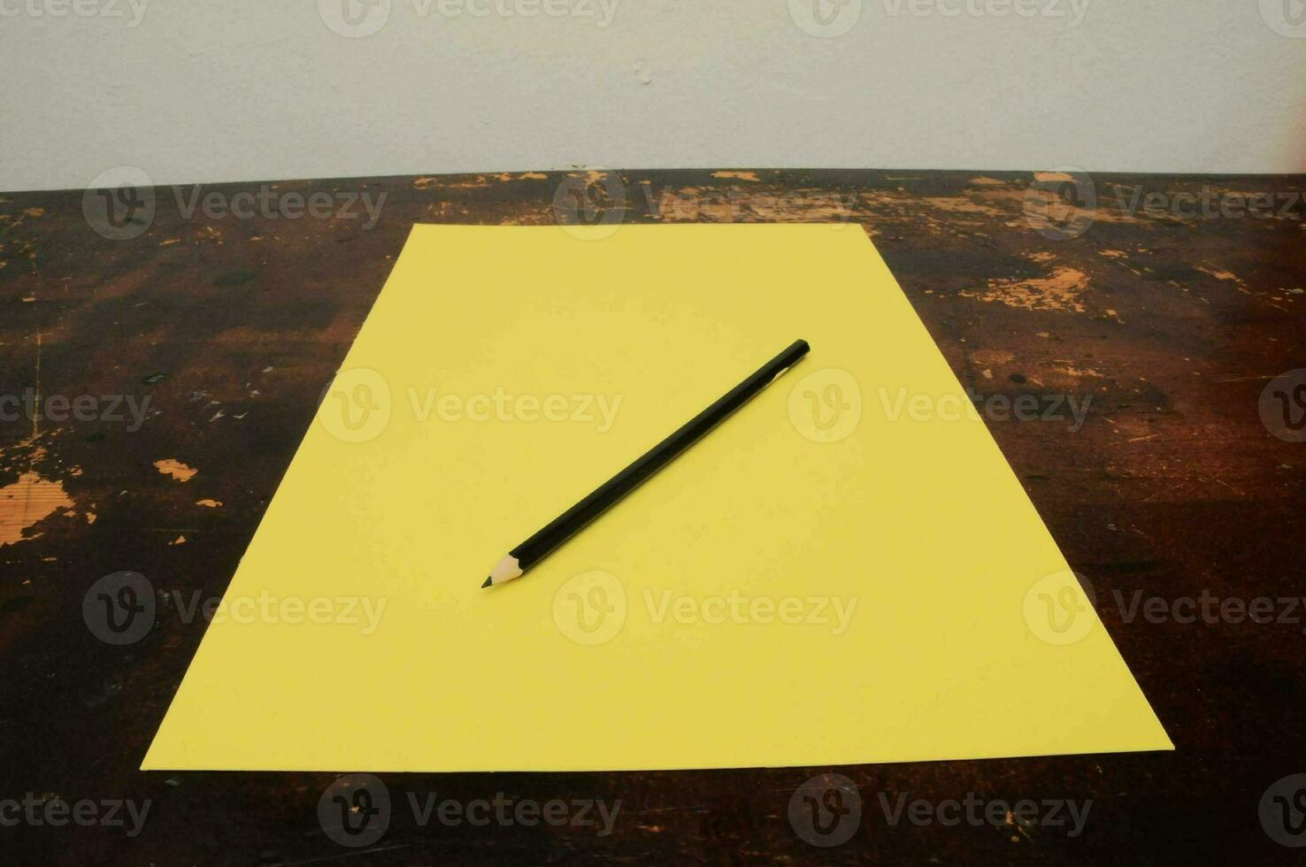un' matita seduta su superiore di un' giallo foglio di carta foto