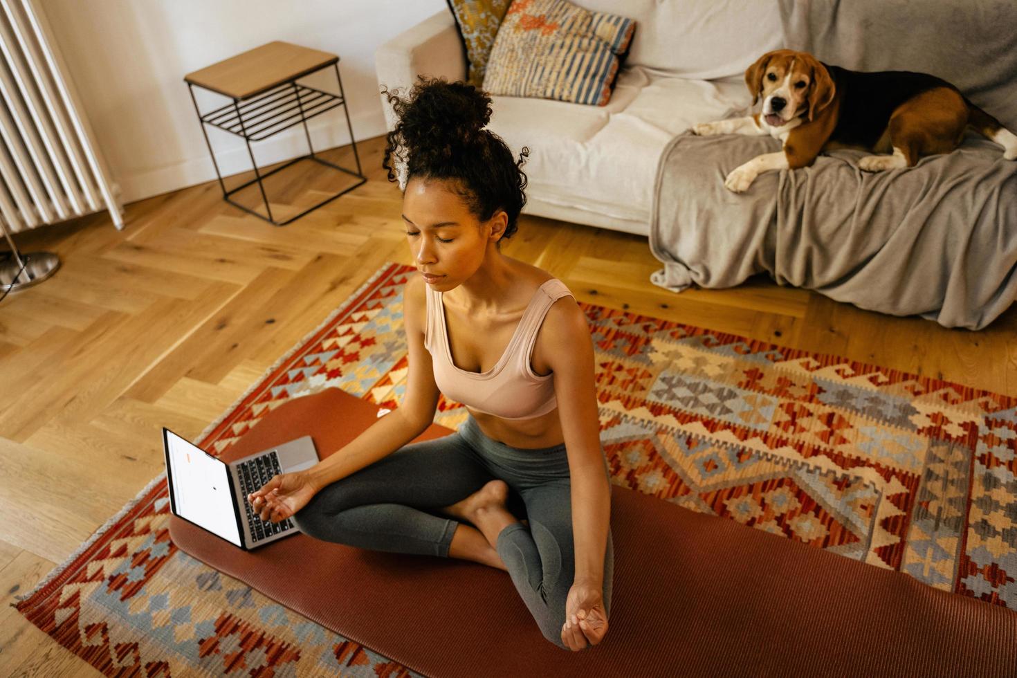 giovane donna nera che medita durante la pratica dello yoga con il suo cane foto